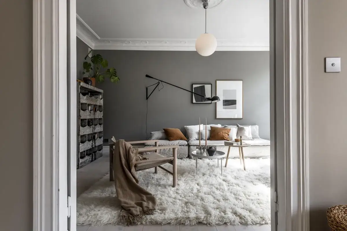 Soggiorno moderno con pareti color grigio piombo, divano modulare, tappeto lanoso e poltrona in legno.