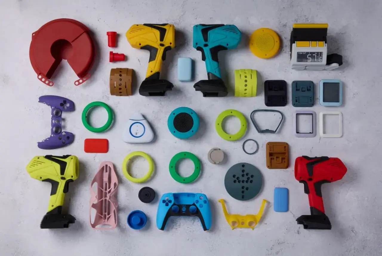 A vibrant collection of objects showcasing the versatility of color 3d printing, from game controllers and drill-like tools to various components and rings.