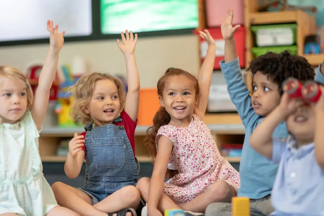 Kinder im Kindergarten zeigen ihre H&auml;nde, ein Zeichen f&uuml;r Partizipation und Freude am Lernen.