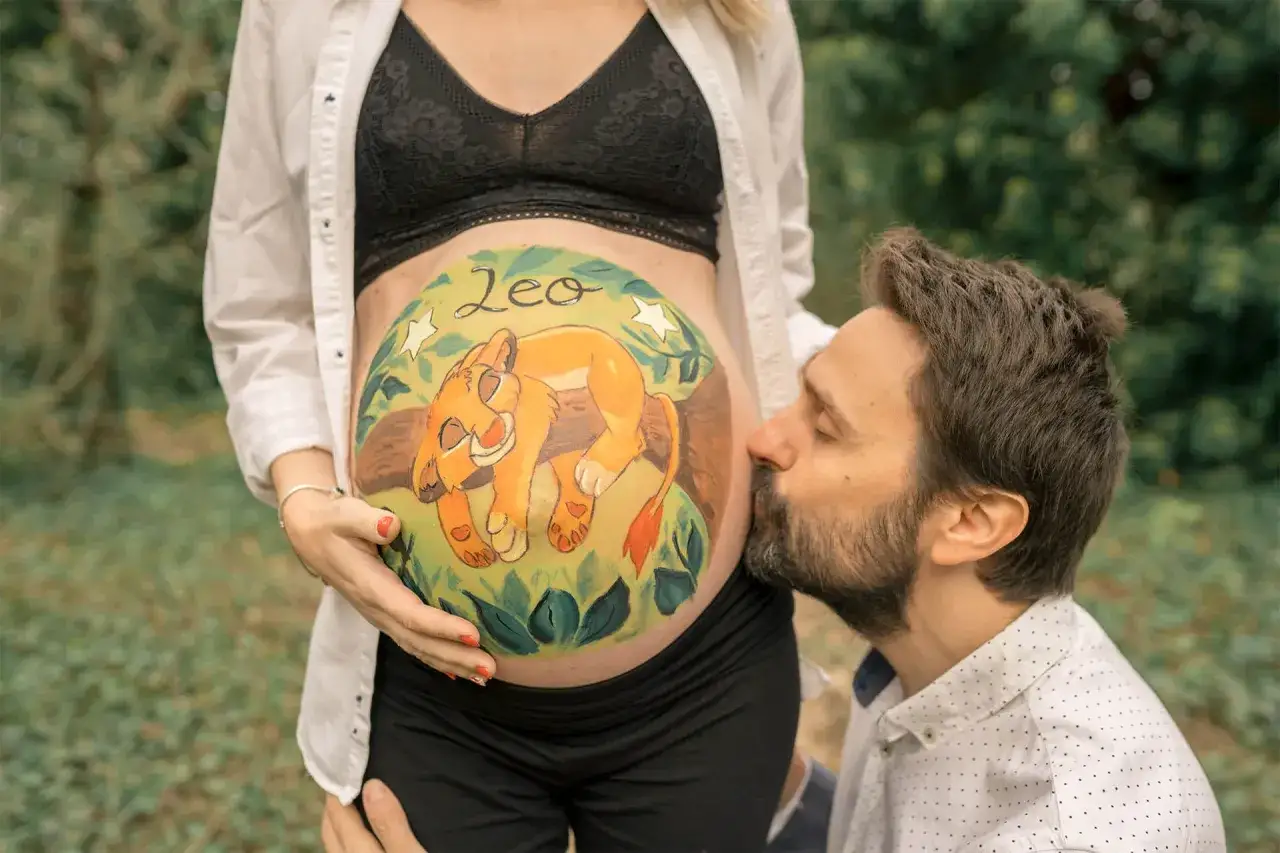 Barriga de embarazada pintada con un león bebé y el nombre 