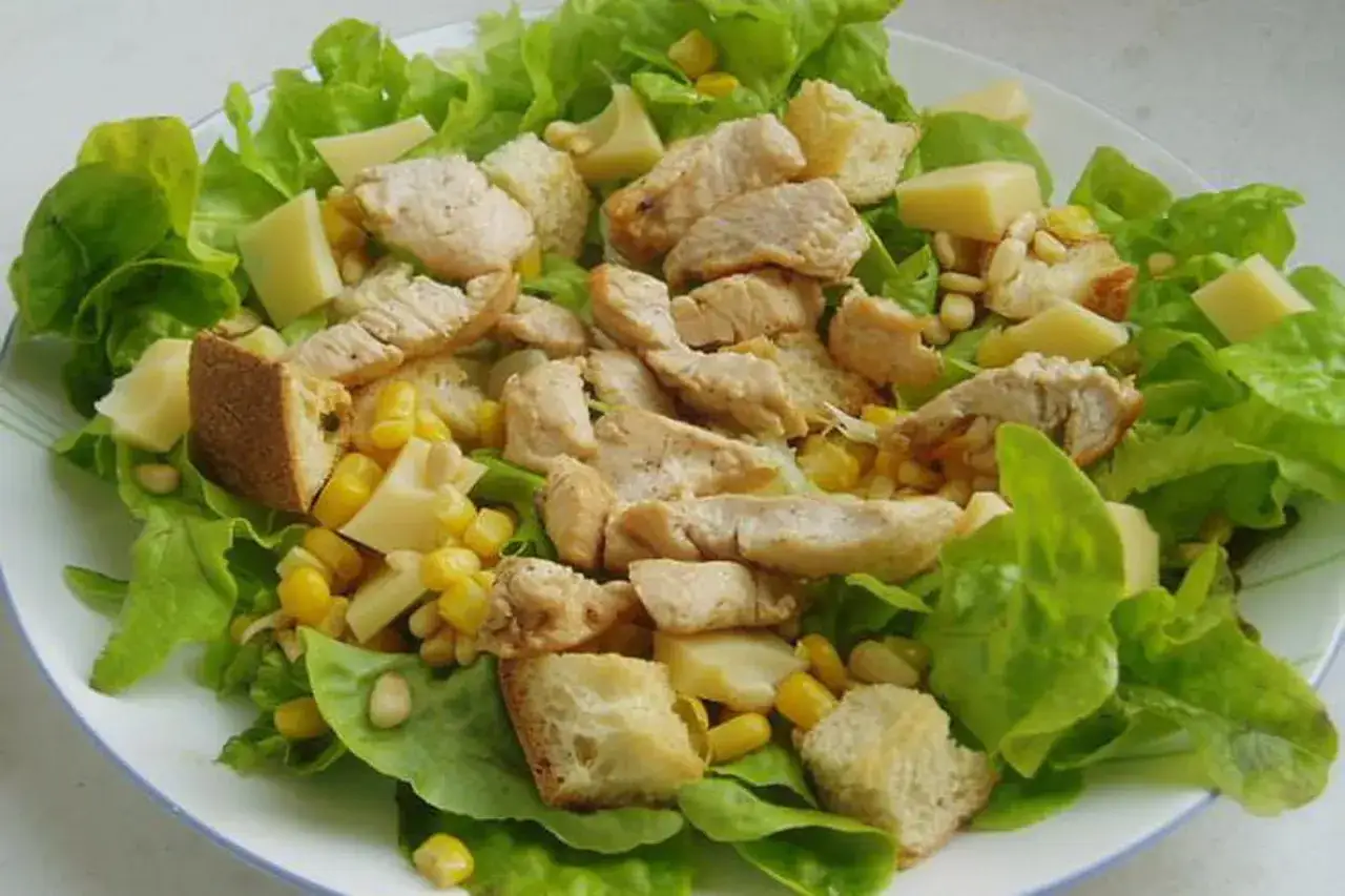 Salade composée avec du poulet grillé, du maïs, des croûtons et des dés de fromage. Quelle viande dans une salade composée !