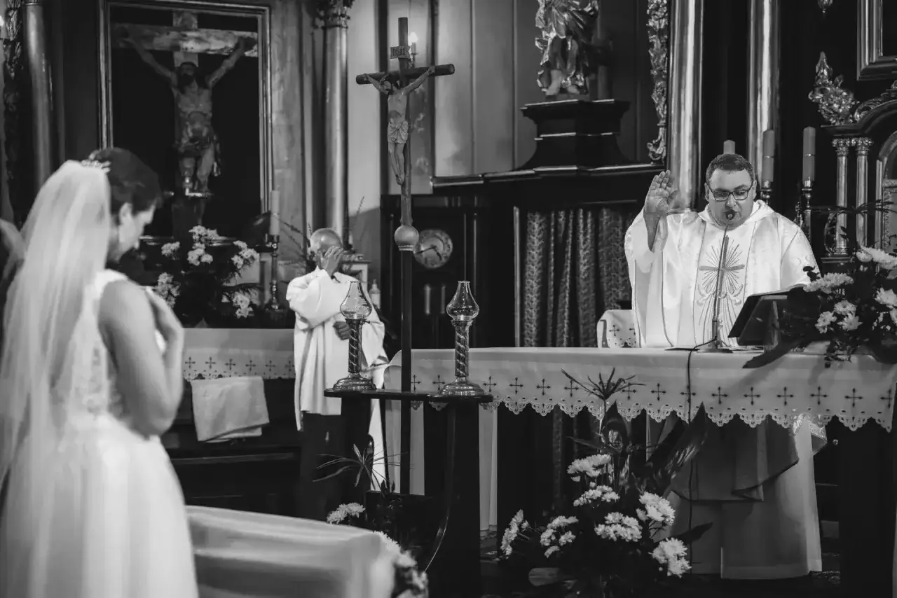 Ślub w kościele. Ksiądz błogosławi parę, która niedługo będzie wiedzieć, ile trwają nauki przedmałżeńskie.