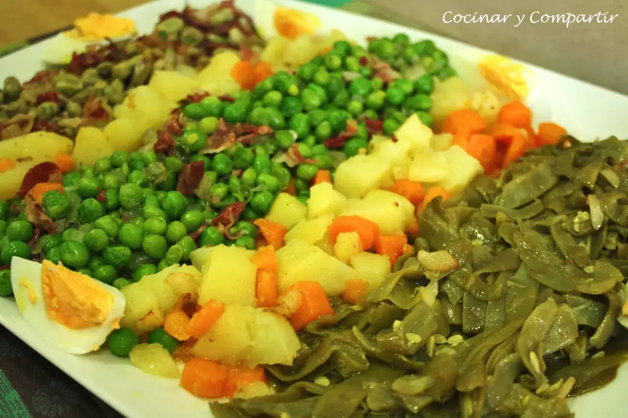 Un plato con un panache de verduras: guisantes, patatas, zanahorias y jud&iacute;as verdes, adornado con huevo duro.