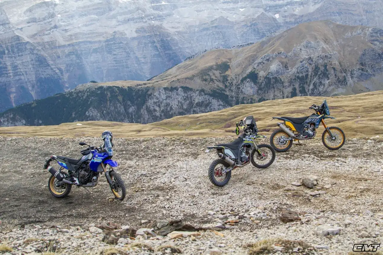 Tres motos de enduro pro listas para la aventura en un paisaje monta&ntilde;oso rocoso.