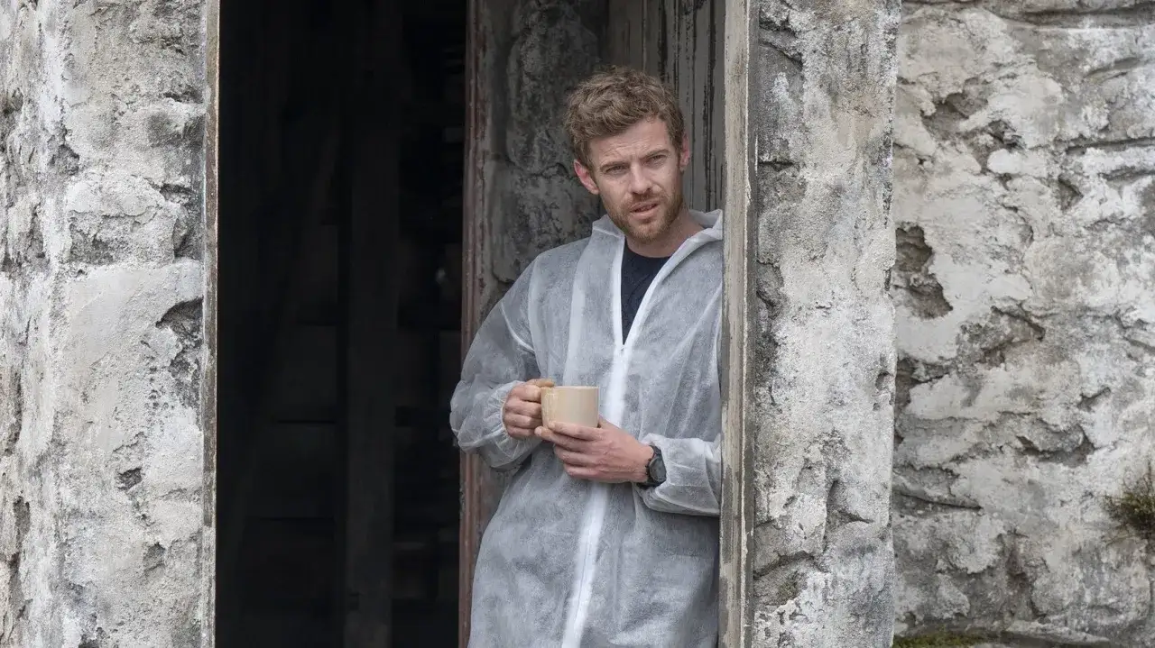 Ein Mann in Schutzanzug h&auml;lt eine Tasse Kaffee. Ein Moment der Ruhe inmitten der 