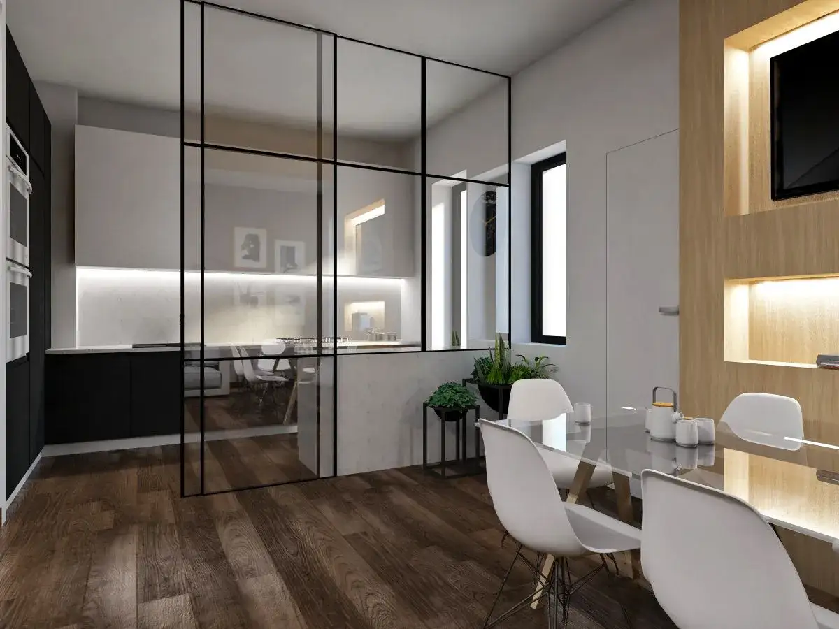 Una moderna zona giorno con tavolo in vetro e sedie bianche, separata da una **finestra interna** in ferro nero da una cucina luminosa con isola.