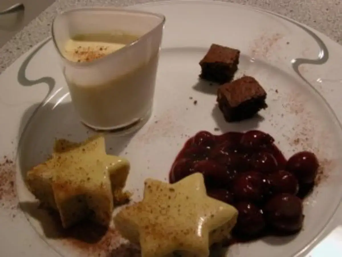 Sterne aus Zimtstern-Eis, garniert mit Kirschen und Brownies, serviert mit einer Vanillesauce.