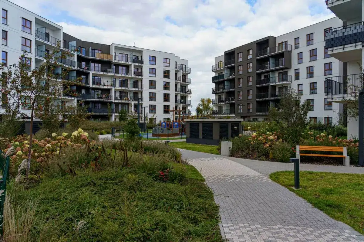Nowoczesne apartamentowce otaczają zielony, zadbany teren z placem zabaw i ławkami. To idealne miejsce na spacer po riviera park.