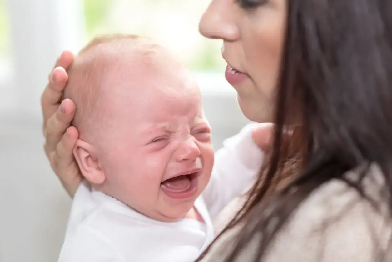 Un beb&eacute; enfadado llora desconsoladamente mientras su madre intenta calmarlo.