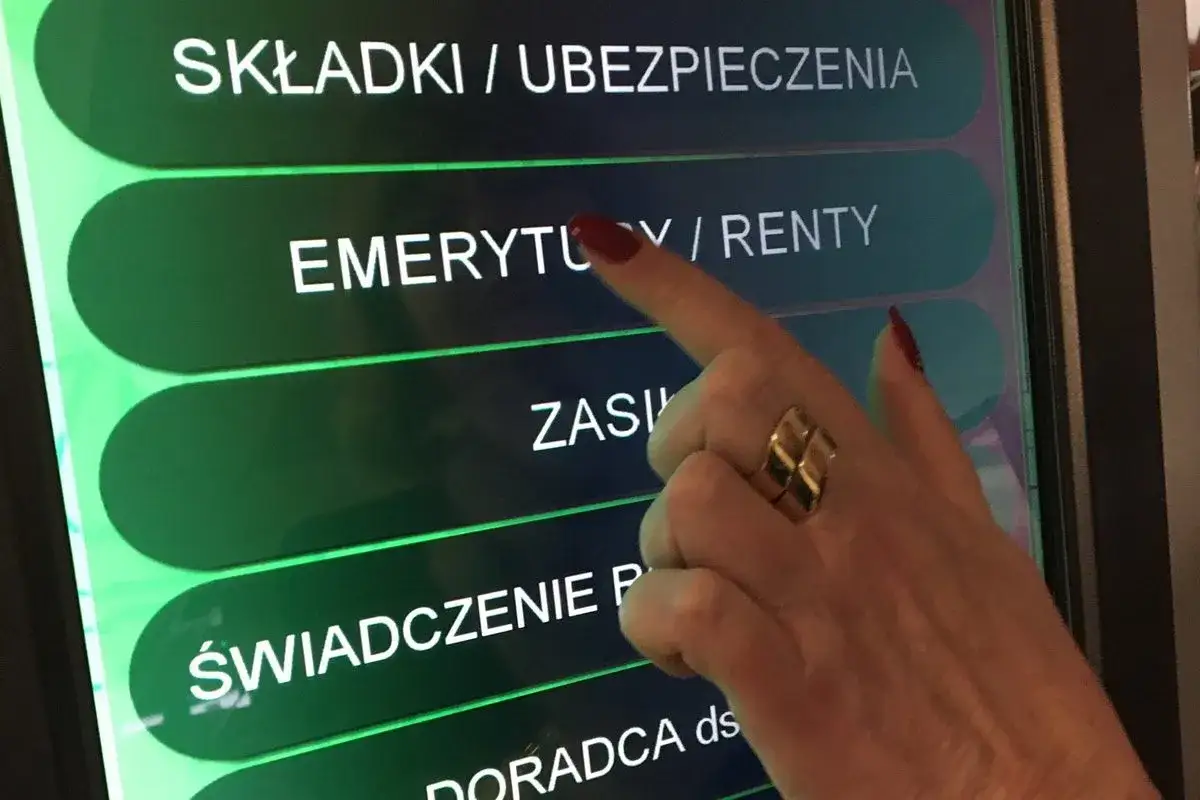 Dłoń z pierścionkiem dotyka ekranu, wybierając