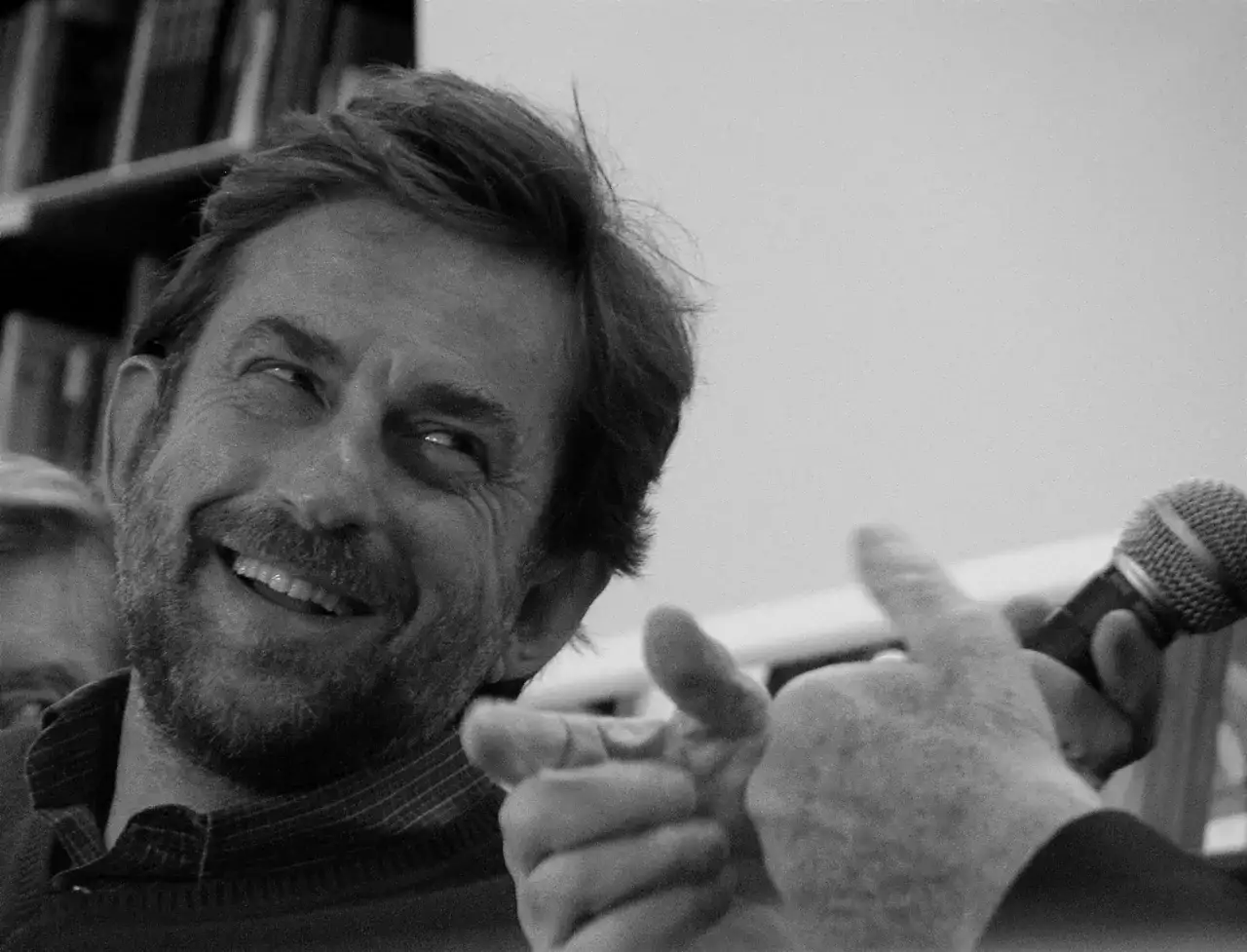 Nanni Moretti sorride e indica, con un microfono in mano, pronto a raccontare una storia.