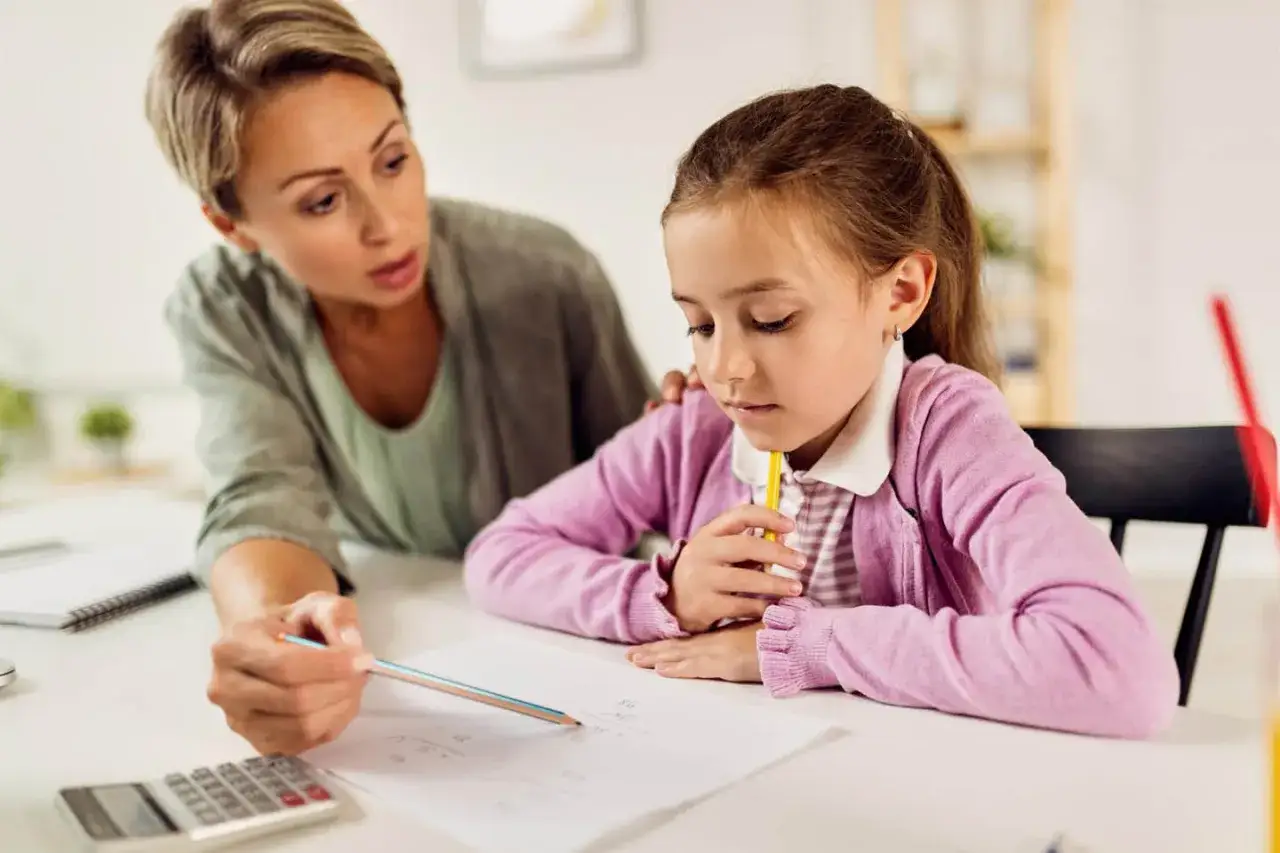 Lehrerin erklärt einem Mädchen Mathe. Die schlechten Noten wegen Faulheit sind ein ernstes Thema.