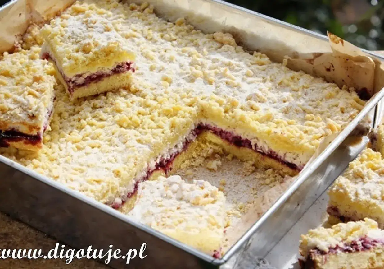 Pyszne ciasto z dżemem z czarnej porzeczki, posypane cukrem pudrem i kruszonką. Idealne na deser.