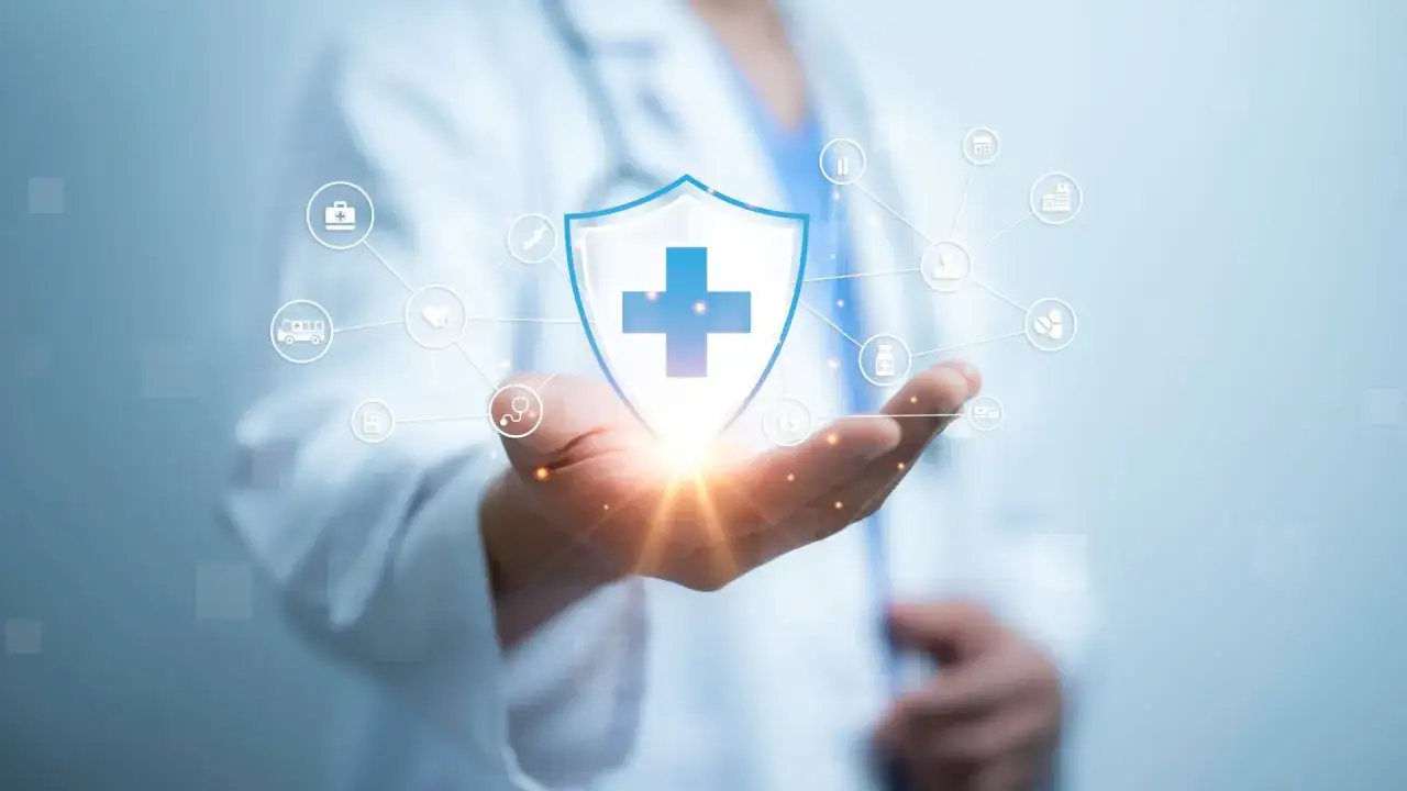 Mano di medico che protegge uno scudo con croce blu, simbolo di cura e salute. Nessuna colpa lieve medico, solo assistenza.