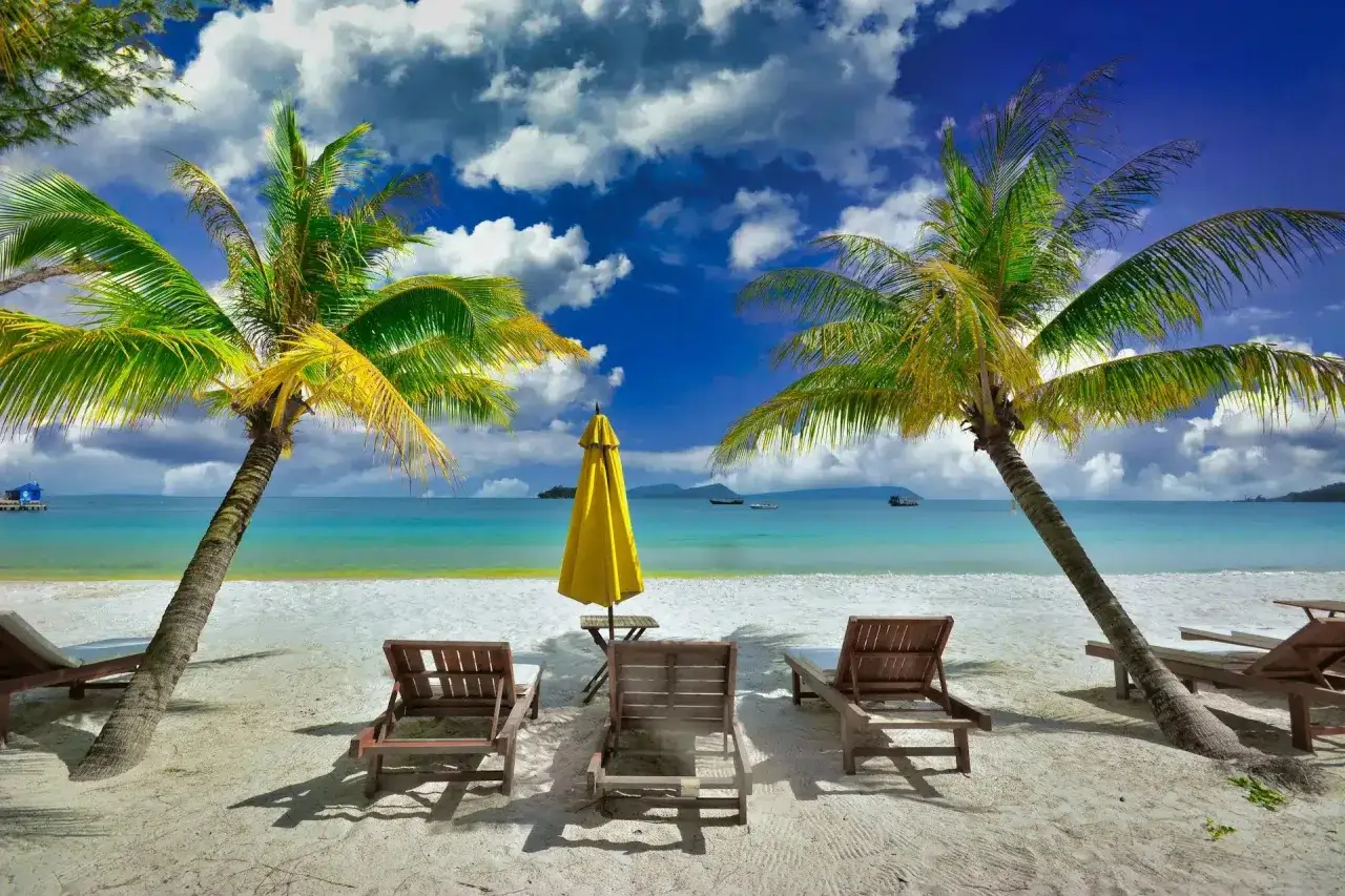 Palmy, leżaki i żółty parasol na rajskiej plaży. Idealne miejsce, by sprawdzić, gdzie najcieplej we wrześniu.