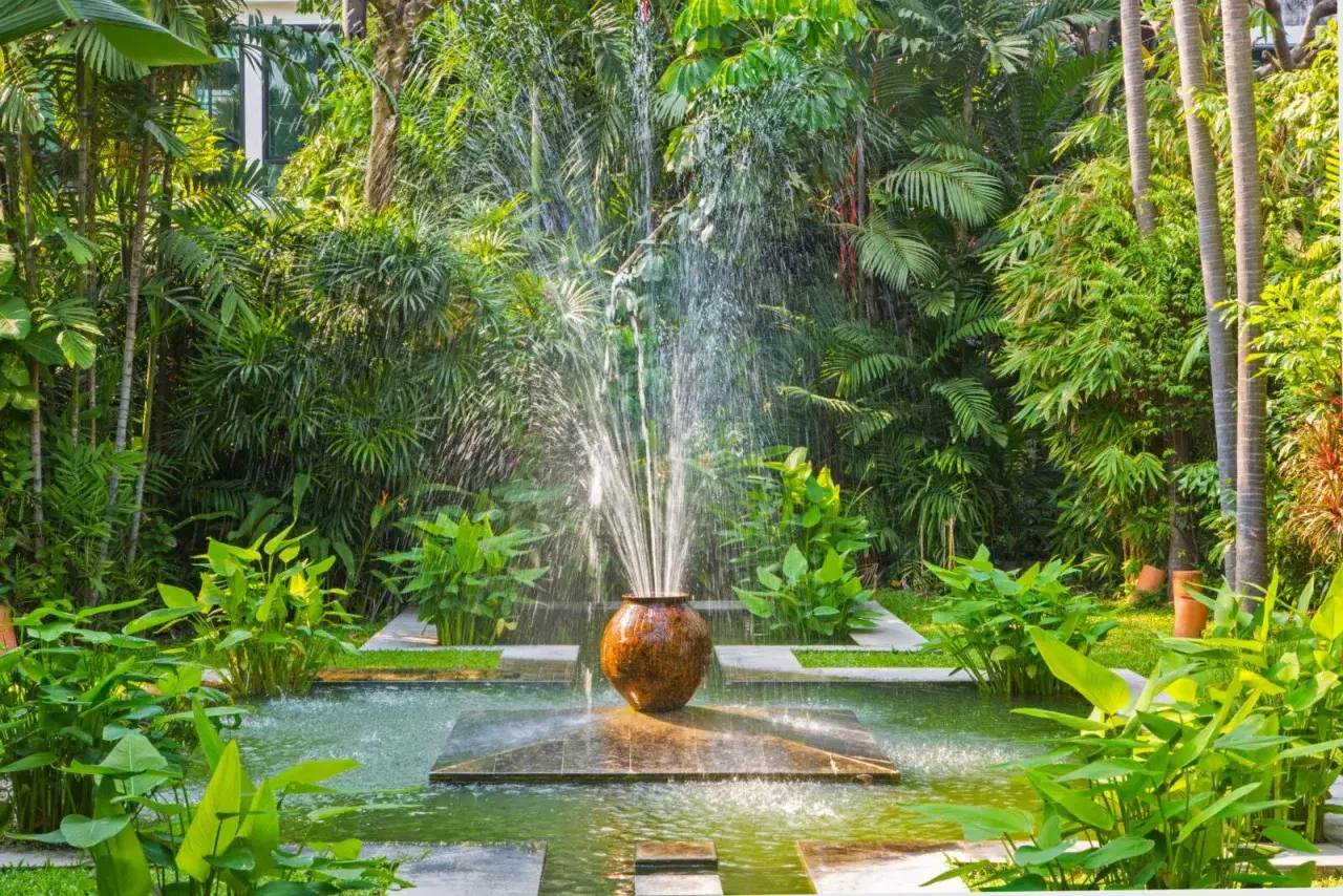 Fontaine d'eau jaillissant d'un pot en terre cuite, au cœur d'un jardin luxuriant. Une **original deco jardin recuperation** qui invite à la sérénité.