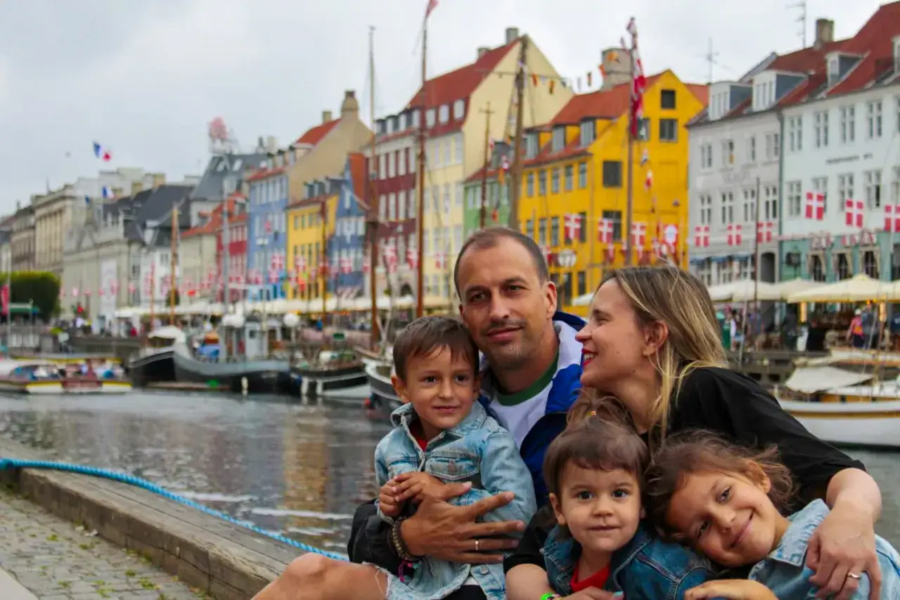 Familia feliz disfrutando de un día en Copenhague con niños, con los coloridos edificios de Nyhavn de fondo.
