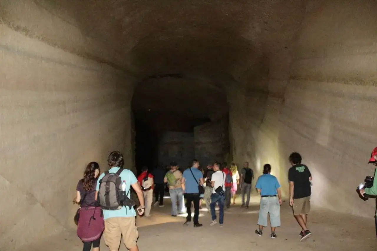 Un grupo de personas explora un túnel en el Sacromonte de Almería, con paredes de roca natural iluminadas por linternas.