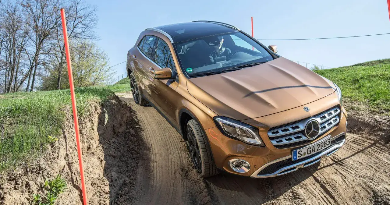 En brun Mercedes GLA testas i terr&auml;ng, med hjulen p&aring; en lerig stig.