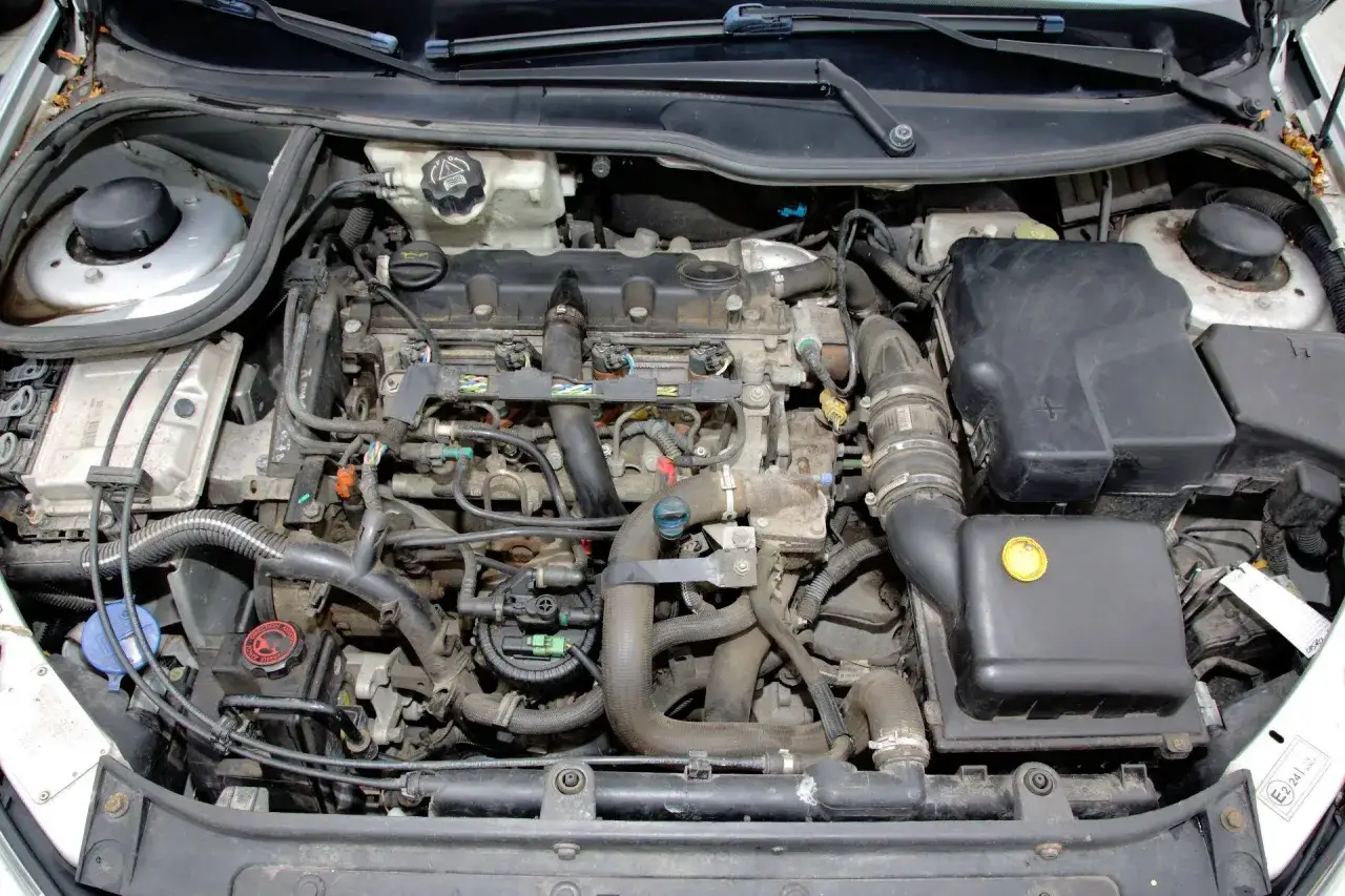 Silnik Peugeot 206 1.4 benzyna, widok z góry. Widać przewody, filtry i inne elementy układu napędowego.