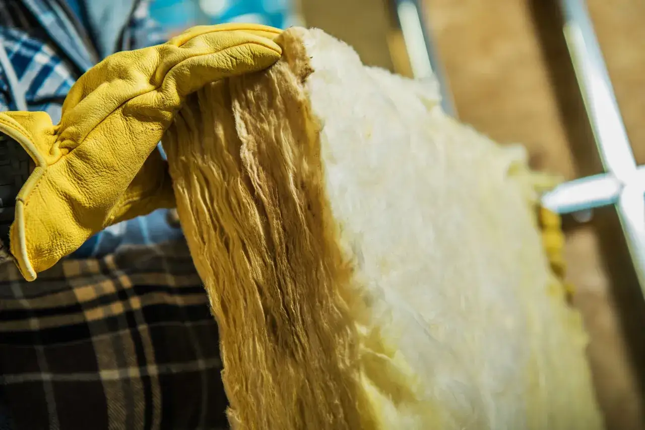Main isolante en laine de verre, pr&ecirc;t &agrave; &ecirc;tre recycl&eacute; &agrave; la d&eacute;chetterie. Un gant jaune prot&egrave;ge la main.