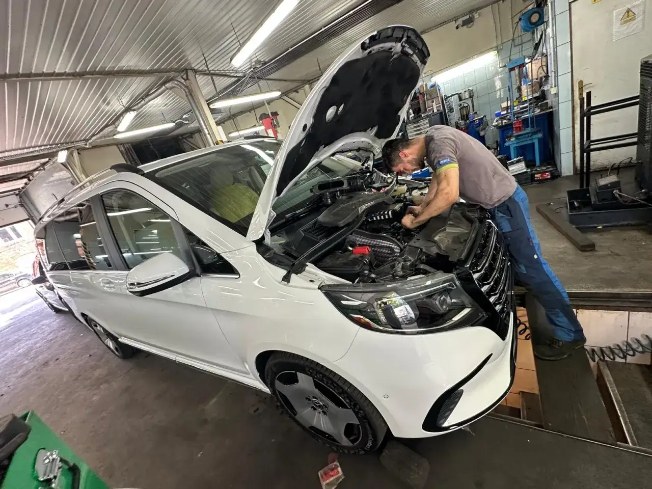 Mechanik pracuje przy silniku białego vana, kt&oacute;ry stracił moc. Auto nie ma mocy benzyna, więc wymaga naprawy.