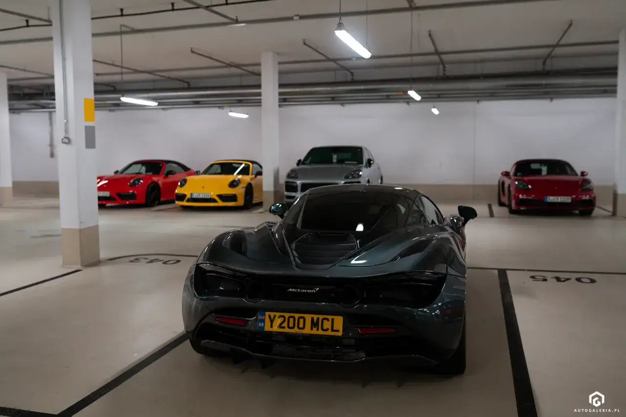 Mclaren 720S cena: ciemnoszary supersamochód z tablicą rejestracyjną Y200 MCL, obok czerwone i żółte Porsche, szare Porsche Cayenne.