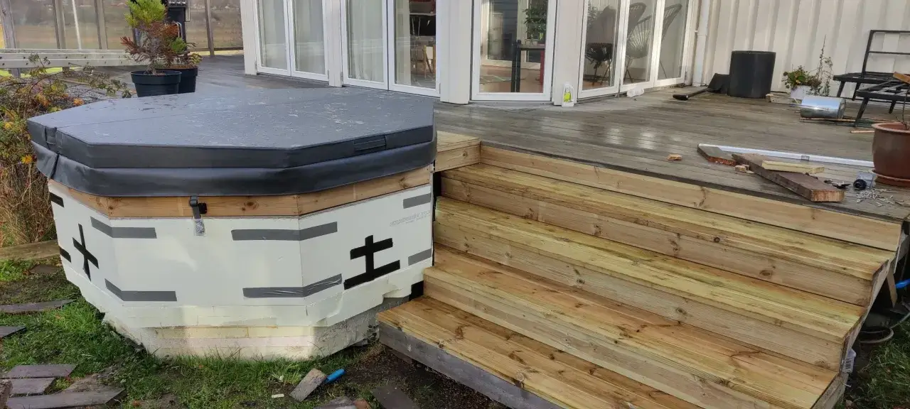 Pågår arbete med att bygga in badtunna i altan. En ny trappa i trä leder upp till altanen.