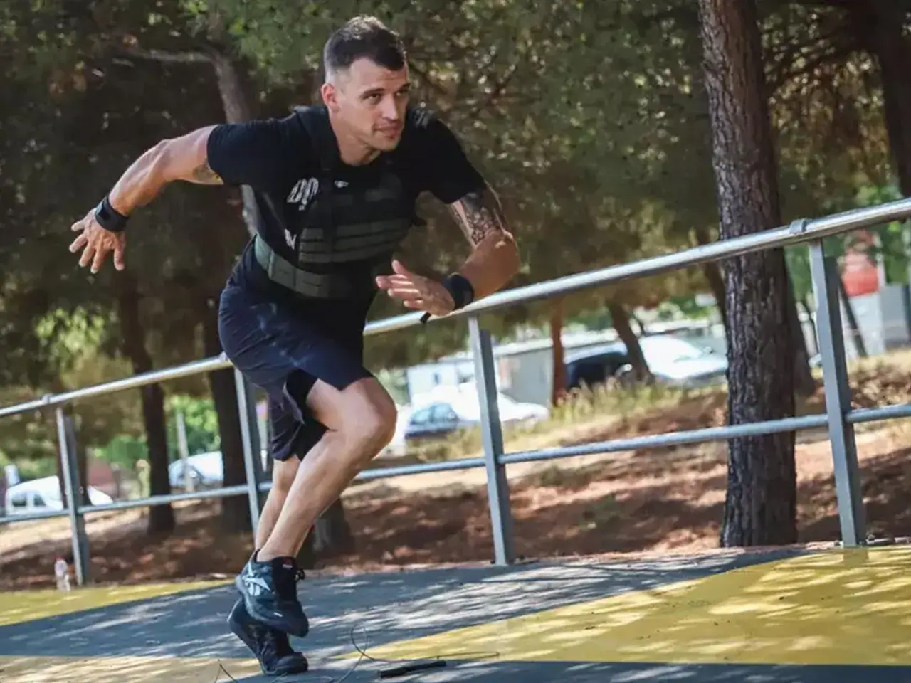 Un homme court avec un gilet lesté, s'entraînant en extérieur. Ses muscles sont tendus, il est concentré sur son effort.
