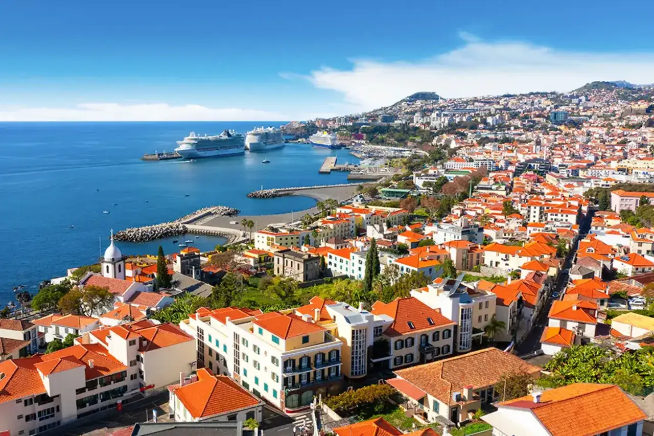Widok na Funchal z portem, statkami wycieczkowymi i wzgórzami. Odkryj liczne atrakcje Funchal, od urokliwego Starego Miasta po malownicze widoki.