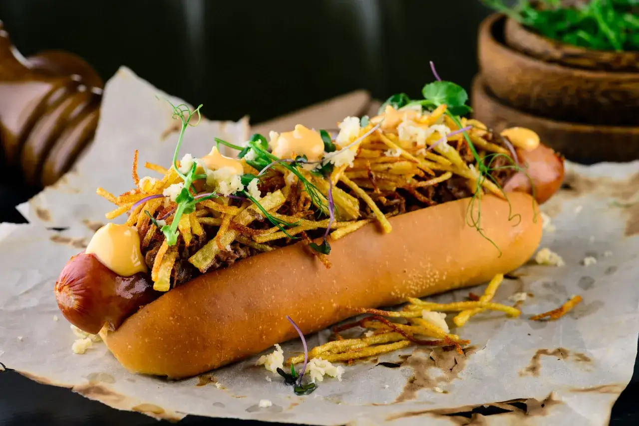 Pyszny hot dog z frytkami z frytkownicy powietrznej, polany sosem.