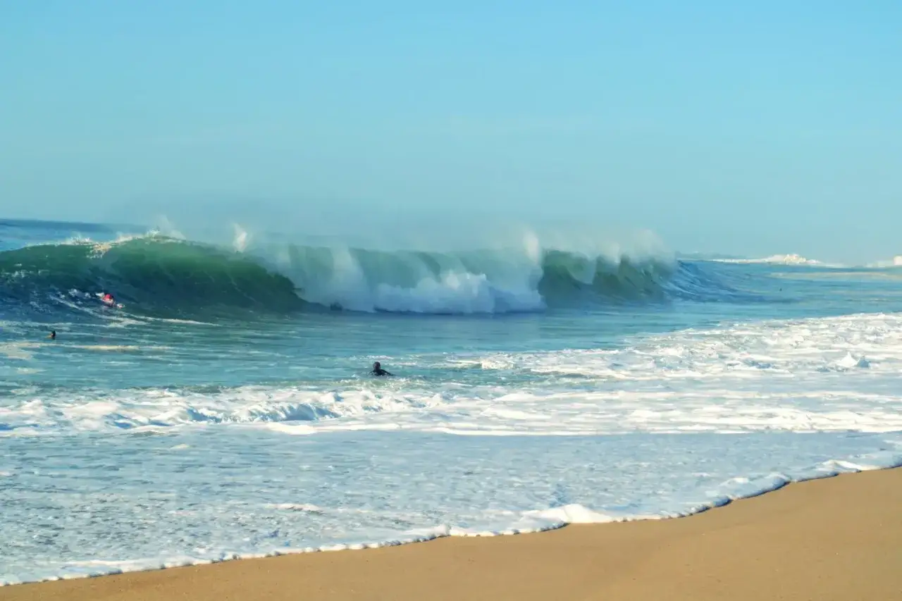 Olas gigantes rompiendo en la costa, surfistas esperando la ola perfecta. ¡Esto es lo que ver en las Landas!