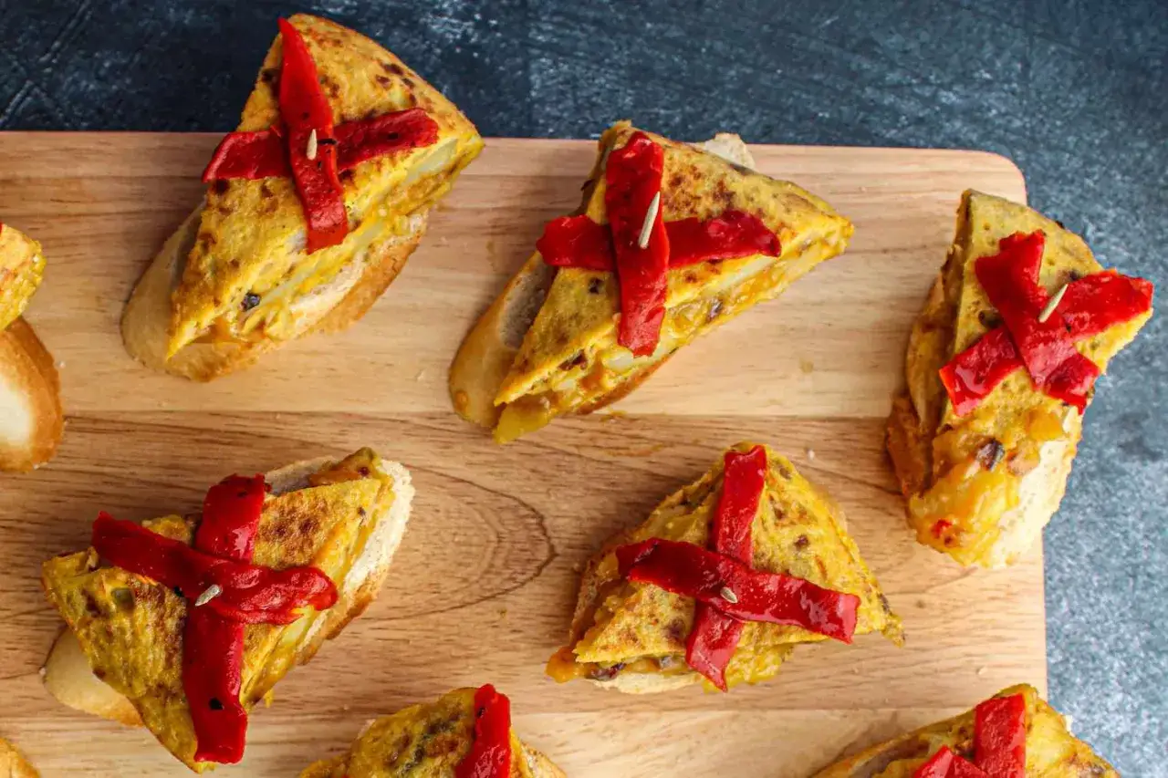 Delicious pincho recipes featuring tortilla española on toasted bread, topped with vibrant red peppers. Perfect for tapas!