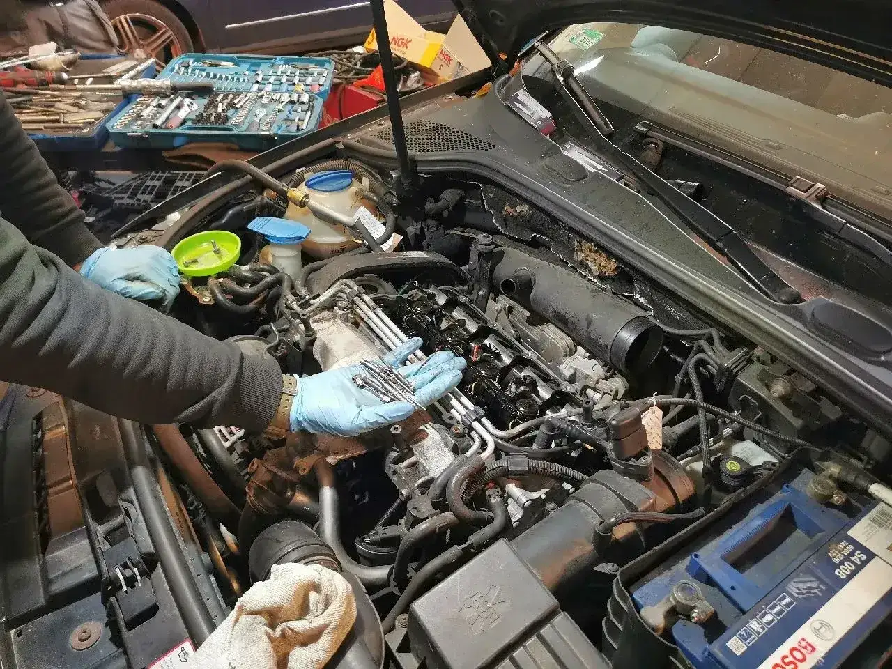 Mechanik wymienia świece żarowe w silniku diesla. Zastanawiasz się, ile kosztuje wymiana świec żarowych w dieslu?