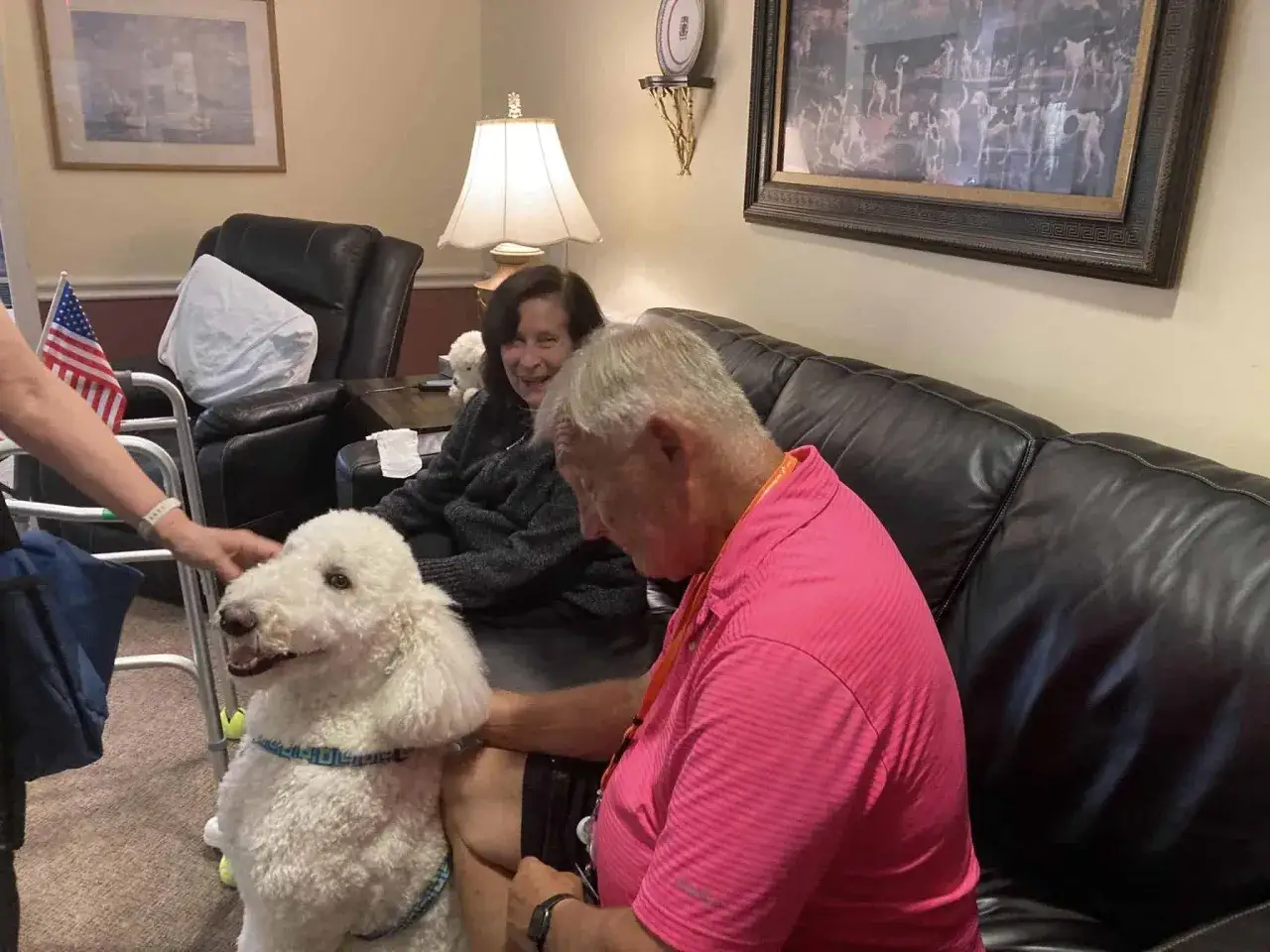 Un cane bianco e soffice interagisce con persone sedute su un divano. Sembra che questi animali stiano salutando, portando gioia.