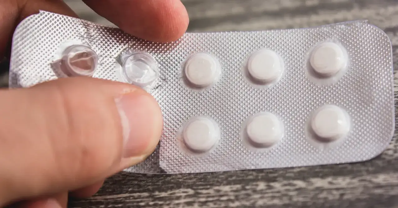 Dłoń otwiera opakowanie tabletek. Flukonazol bez recepty jest łatwo dostępny, by szybko pozbyć się infekcji.