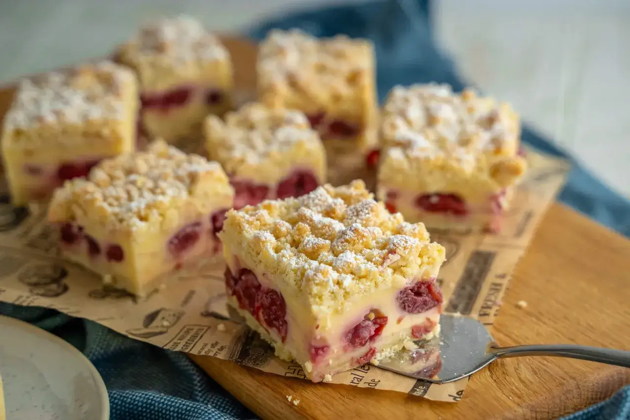Omas Kirschkuchen mit Pudding, saftig und mit Streuseln bestreut, wird auf einem Holzbrett serviert.