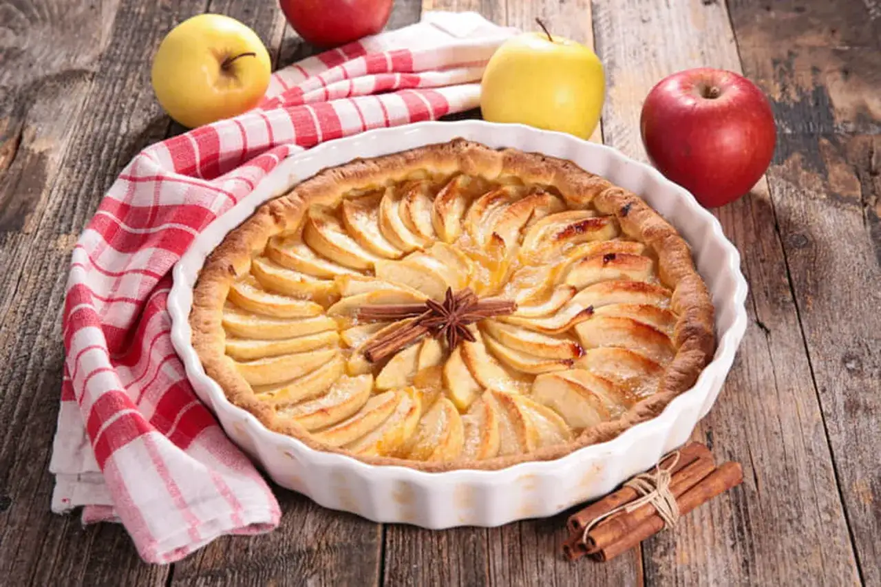 Un délicieux appareil tarte aux pommes, orné d'une étoile de badiane et de bâtons de cannelle, prêt à être dégusté.