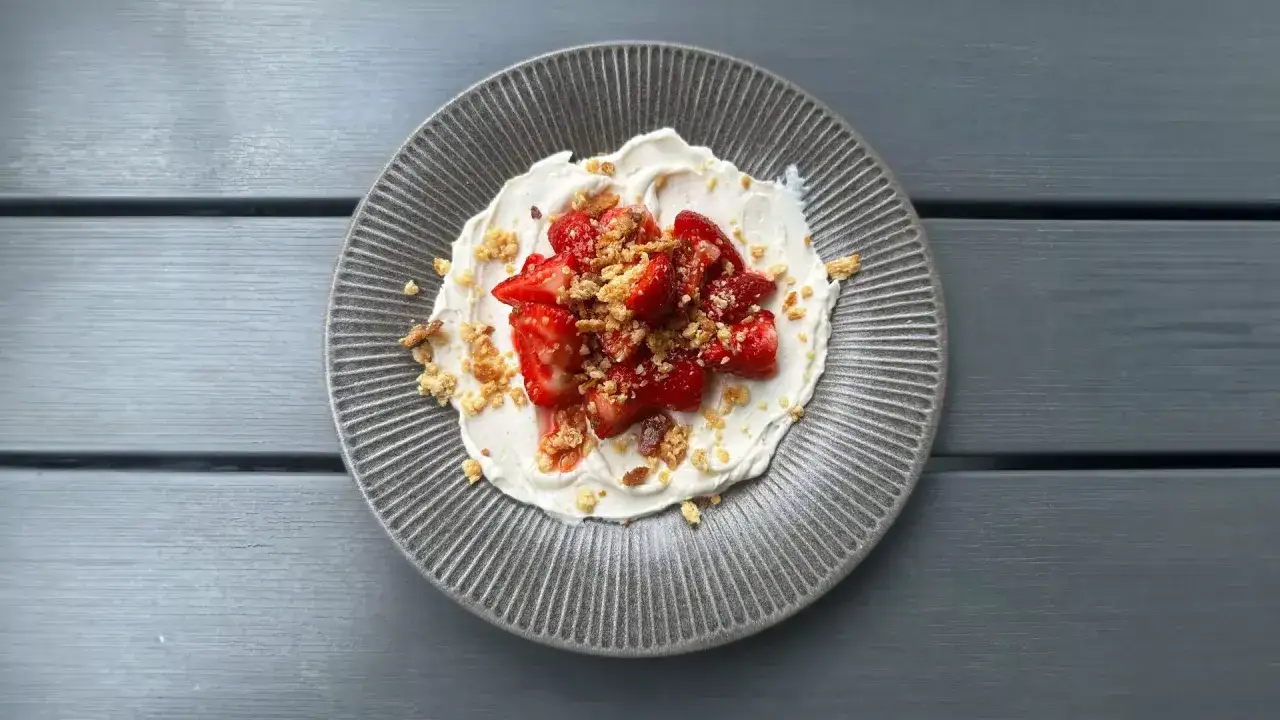 En tallrik med kr&auml;mig dessert toppad med saftiga, limemarinerade jordgubbar och smulor. En h&auml;rlig sommarfavorit!
