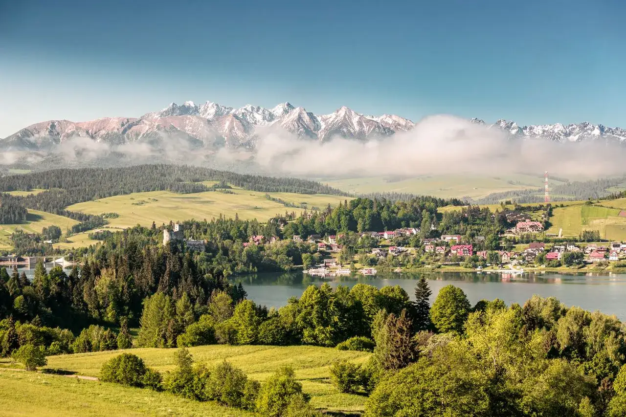 Zamek Czorsztyn g&oacute;ruje nad jeziorem, a w tle widać ośnieżone Tatry.