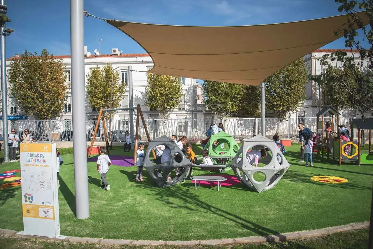 Un parque infantil en Mérida con niños jugando en estructuras modernas y columpios.