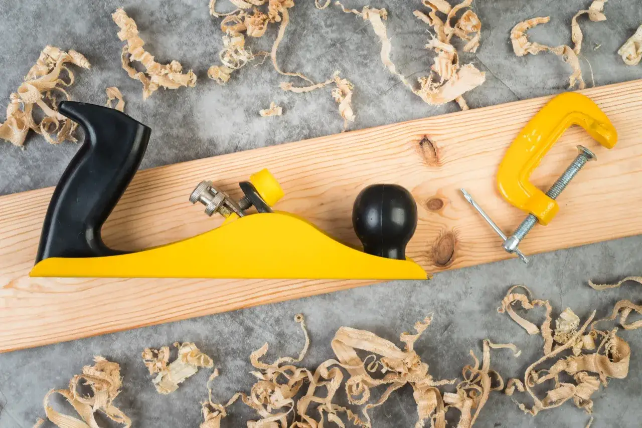 Outil de menuiserie jaune et noir sur une planche de bois, entour&eacute; de copeaux de bois. L'egrenage est pr&ecirc;t pour le travail.