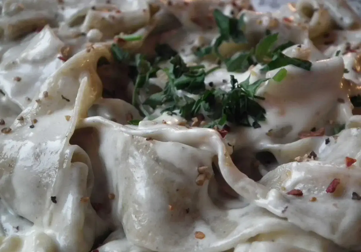 Kremowy sos do spaghetti z posiekaną natką pietruszki i kawałkami orzechów.