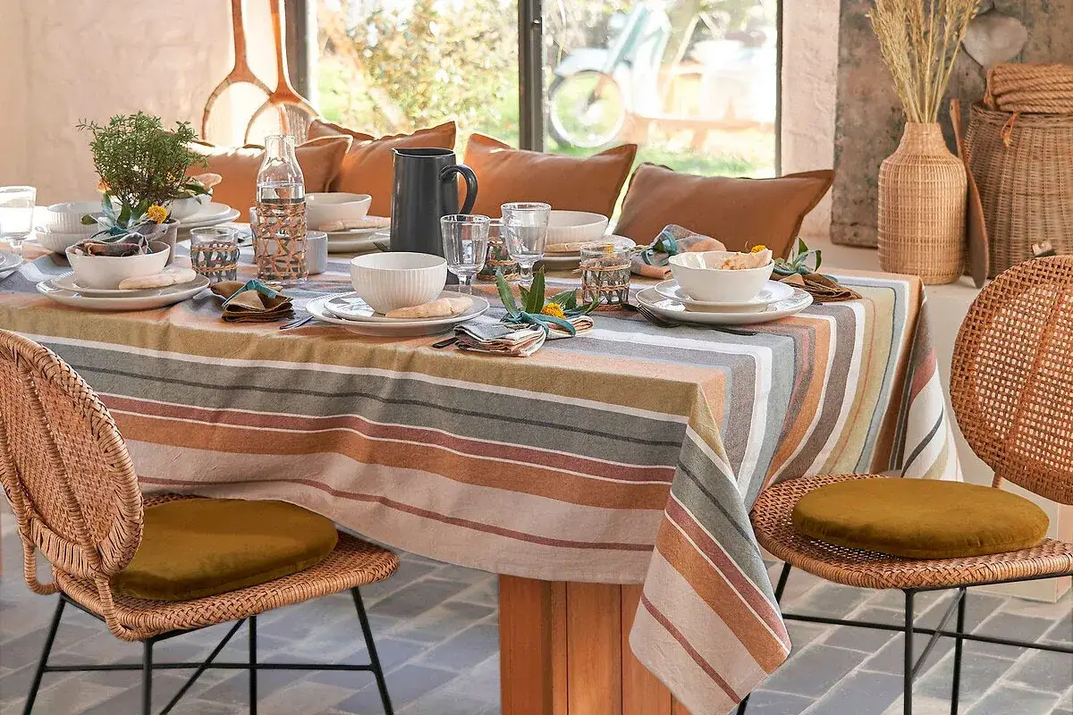 Une table dress&eacute;e avec une nappe ray&eacute;e aux tons chauds et naturels. Le choix de cette nappe est parfait pour une ambiance cosy.