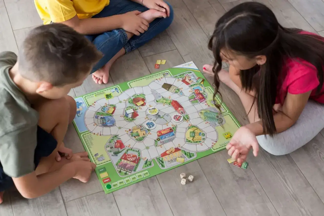Ni&ntilde;os jugando juegos cooperativos para adolescentes en un tablero colorido.
