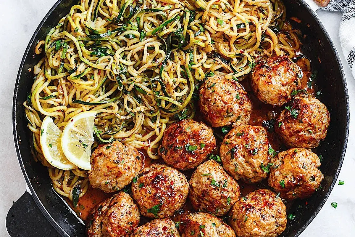 Albóndigas jugosas con fideos de calabacín, una de las mejores recetas con calabacín. Servido con rodajas de limón.