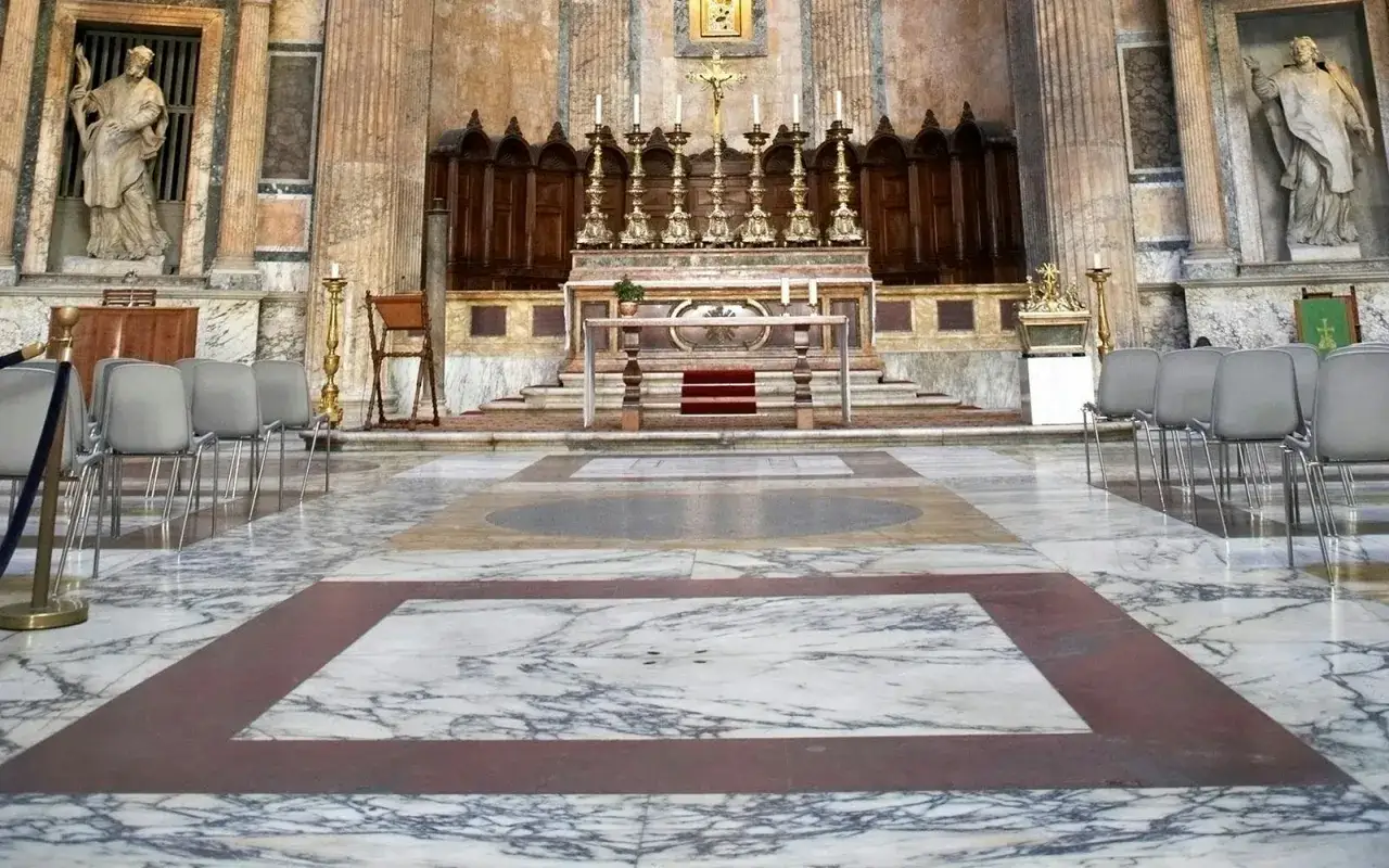 Int&eacute;rieur du Panth&eacute;on de Rome : chaises grises align&eacute;es sur un sol en marbre, devant un autel orn&eacute; de cand&eacute;labres dor&eacute;s.