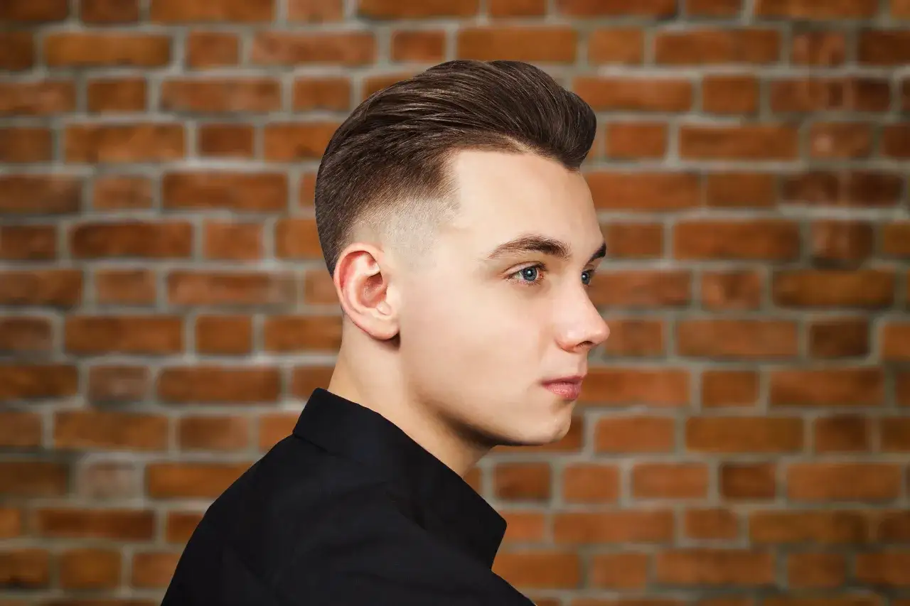 Młody mężczyzna z modną fryzurą męską, która dodaje mu uroku i odmładza.