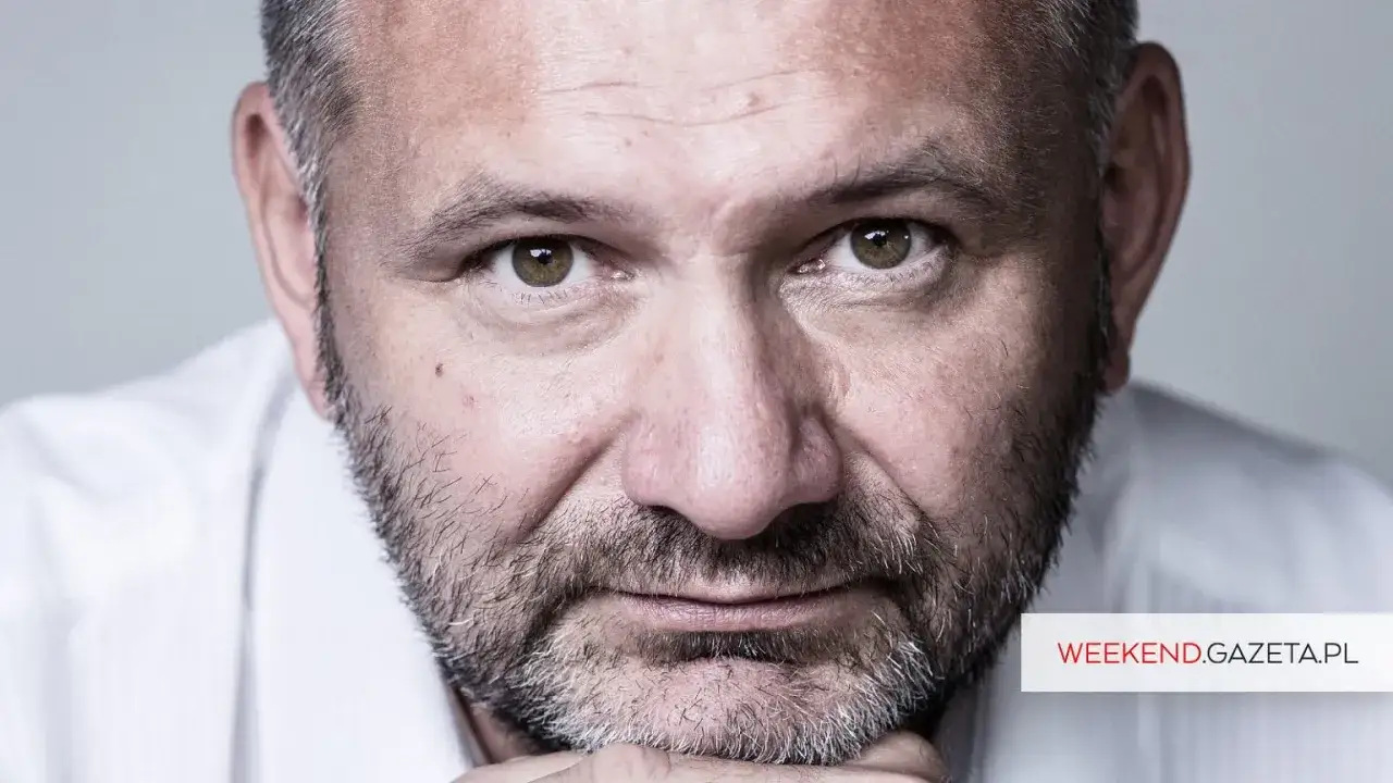Zbliżenie na twarz Waldemara Żurka, z siwiejącą brodą i zmarszczkami. Może opowiadać o swoim życiu, a jego żona słucha.