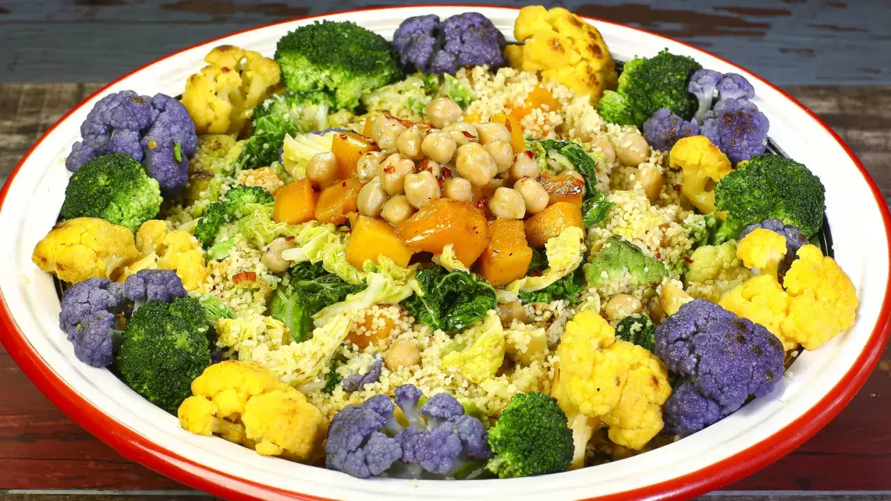 Un colorato piatto di cous cous con verdure invernali: cavolfiore viola, giallo, broccoli, zucca e ceci. Perfetto per le ricette cous cous invernale.
